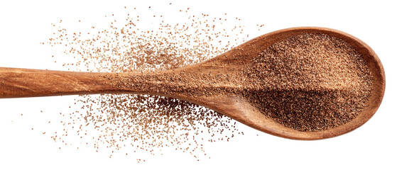 Wooden spoon filled with ground spice, scattered on black
