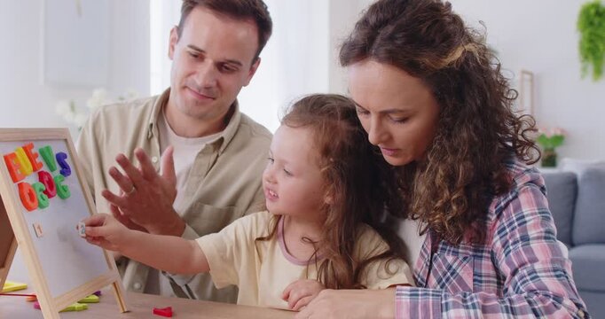 Family with daughter learning at home play. Parents guide child girl at a magnetic board, sorting letters, numbers to build counting, literacy, and education. Playful learning, development and study.