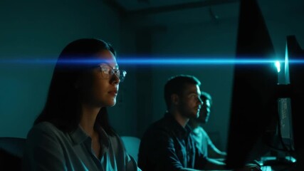 Asian female programmer and male colleagues working late at night in a dark office. Cybersecurity team focused on data analysis on computer screens with blue light flare - Powered by Adobe