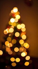 Abstract golden bokeh Christmas tree against a warm, dark background creating a festive, dreamy, and soft atmosphere