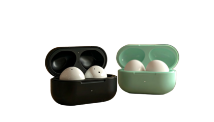 Two sets of wireless earbuds in their charging cases, one black and one teal, on black backdrop