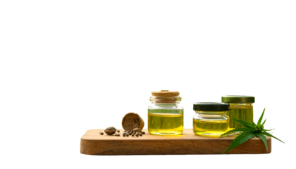 Golden liquid in jars with hemp leaf on wooden board, against black background