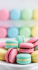 Obraz premium Colorful meringue based cookies stacked neatly on a white plate with more blurred items in background