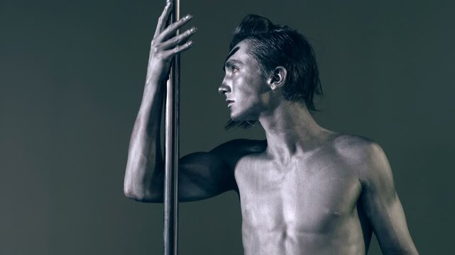 Pole dancer. Guy does gymnastic exercises on pole dance. Pole dancing for slim fitness body. Flexibility. Pole dance. Pylon dancing strength, flexibility, and grace. Strip muscular man dancer.