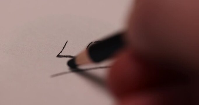 drawing on paper with a wooden pencil with a black lead, cross out the word love written in black pencil on paper, close up