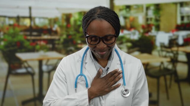 Woman doctor with stethoscope feeling grateful on outdoor cafe terrace smiling peacefully in daytime.