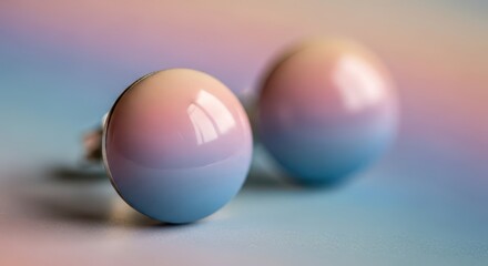 Close up of two small, spherical objects featuring a smooth, polished surface with a soft color gradient background.