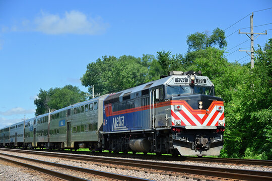 A Metra commuter train traveling through a tree-lined right-of-way during its outbound journey from Chicago in the city's western suburbs. 