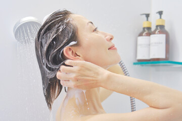 シャワーで髪を洗い流す女性