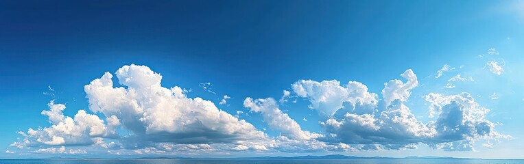 Bright blue sky filled with towering white cumulus clouds above a calm sea and distant low coastline, evoking peaceful expansive serenity