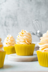 yellow cupcake with orange buttercream frosting on white background, tall buttercream frosting on yellow cupcakes
