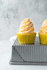 yellow cupcake with orange buttercream frosting on white background, tall buttercream frosting on yellow cupcakes