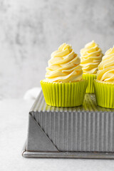 close up view of cupcakes in green liners with tall buttercream swirl, green cupcakes with vanilla buttercream with a marble background