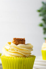 green cupcake with buttercream frosting and a sponge cake garnish on white background, tall buttercream frosting on green cupcakes