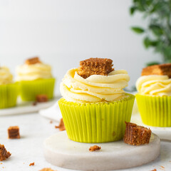green cupcake with buttercream frosting and a sponge cake garnish on white background, tall buttercream frosting on green cupcakes