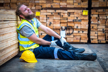 Wood factory worker man having injure at work. Man worker feeling pain in his leg from accident while working in warehouse.. Safety, Industry, Healthcare, Insurance Concept.
