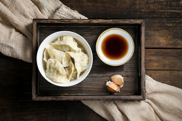 Bowl of boiled chinese dumplings with vinegar and garlic on wooden tray