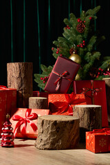 Red presents and wooden stumps are placed beside a decorated Christmas tree. The dark green curtain and soft lighting highlight the holiday spirit in a clean, minimal composition.