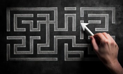 hand drawing an arrow through a white chalk maze on a blackboard conveying focused problem solving and determination