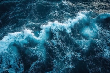 Fototapeta premium Aerial view of deep blue ocean waves with white foamy crests, turbulent water and swirling currents conveying power and serene awe