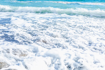 Foamy turquoise sea waves on the shore. Beautiful nature. Relaxation and tranquility. Background. Space for text.