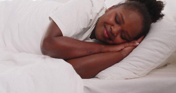 Close up of peaceful relaxed african american woman sleeping in sweet dreams lying on bed in bedroom in morning. Young girl napping with comfort under white cozy linen. 4k video. Slow motion video.
