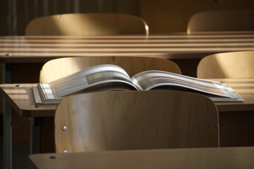 An open book sits on a desk in a sunlit classroom, ready for a new lesson.