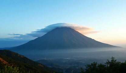 Fototapeta premium A majestic volcanic mountain standing tall beneath a vast blue sky, captured during a clear morning with soft warm light on the horizon.
