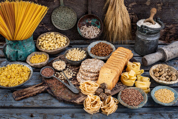 Variety  of carbohydrates like uncooked pasta and  zwieback on the wooden bowl. 