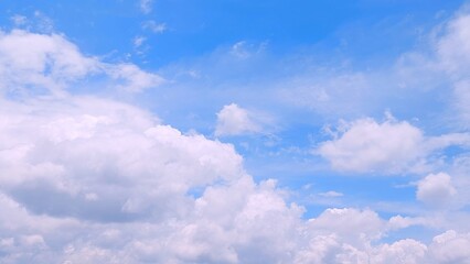 Cumulus clouds clustered in the blue sky. Blue sky with white cloud formations of multiple shapes. Aerial view of cloudscape on sunny day.