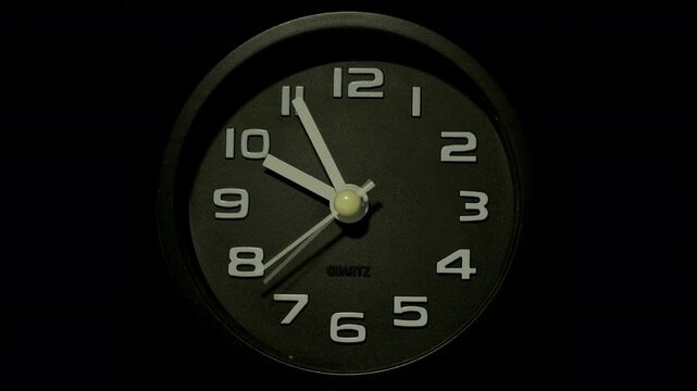 Tme lapse video of a clock time passing over a day to night on black background.