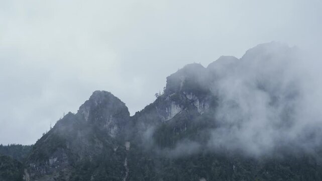 Timelapse of moving fog covering mountain, static.