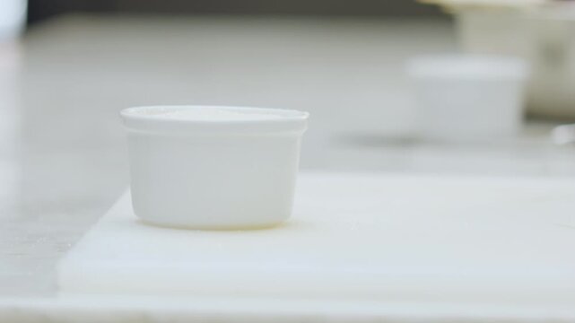 Close-up of a chef placing a ceramic mold on a chopping board. In the background, softly blurred, an aluminum mold can be seen.
