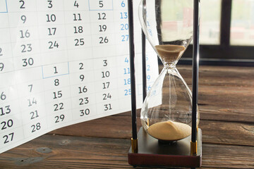 The hourglass and calendar as a symbol of time. The concept of time passing irrevocably.