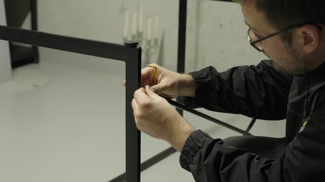 A man assembles a metal frame using an Allen key &mdash; concept of DIY, furniture assembly, craftsmanship, and home improvement.