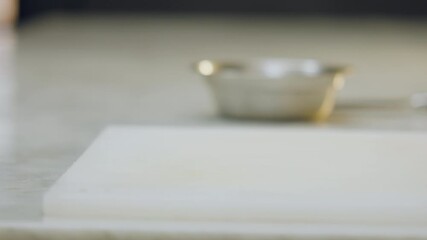 Close-up of a chef placing a ceramic mold on a chopping board. In the background, softly blurred, an aluminum mold can be seen.