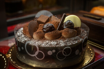 A beautiful, mouth-watering chocolate cake in a pastry shop window. Baked goods for holidays and celebrations. Close-up.