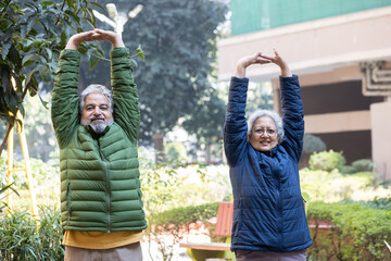 Active Indian senior couple wearing warm cloths do outdoor exercise in winter season. Fit asian...
