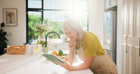 Senior, woman and online recipe with tablet for cooking tutorial or healthy food in home kitchen....
