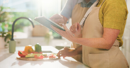 Couple, hands and vegetables with tablet for online cooking tutorial or healthy recipe in kitchen. Closeup, man or woman with technology or ingredients for research, natural organic food or meal prep