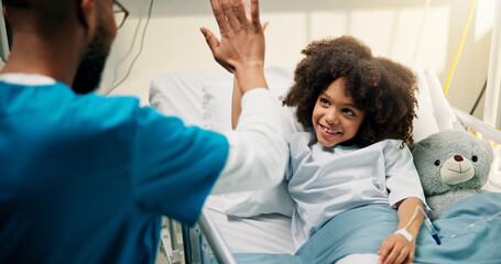 Boy, doctor and high five with smile in hospital bed, happy and care with support for recovery. Pediatrician, child and excited with teddy bear, motivation and celebration with healing at clinic