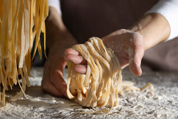 Caucasian female hands holding raw fettuccine noodles after drying