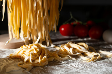 Homemade noodles hanging on wooden dryer rack over messy kitchen table background low angle front view