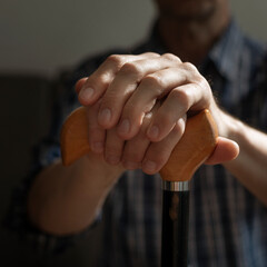 Middle age caucasian man hands holds cane closeup