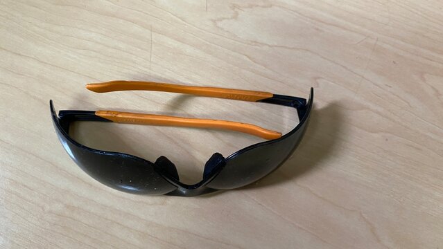 a pair of black safety glasses placed on the table surface. - Powered by Adobe
