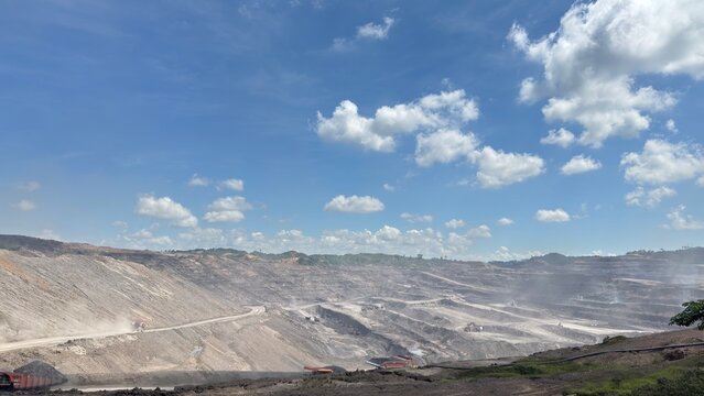 Panoramic wide view of a large scale surface mining site showing geological layers and industrial activity in a deep valley.