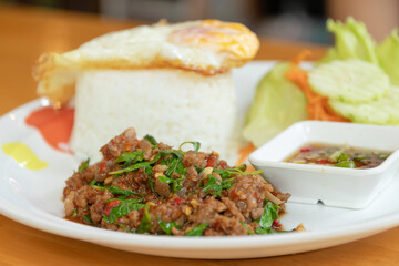 Spicy minced meat with basil served with steamed rice, fried egg and dipping sauce on plate, comforting homemade Thai lunch