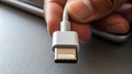 A person holds a USB-C cable connector, showcasing its modern design and functionality against a neutral background.