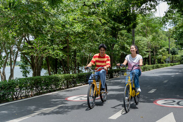 Fototapeta premium Asian young couple dating and biking together on a road in the park. 