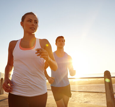 Running, fitness and sunset with couple at beach for workout, cardio challenge and sports athlete. Training partner, wellness and runner race with man and woman on promenade for health and bonding